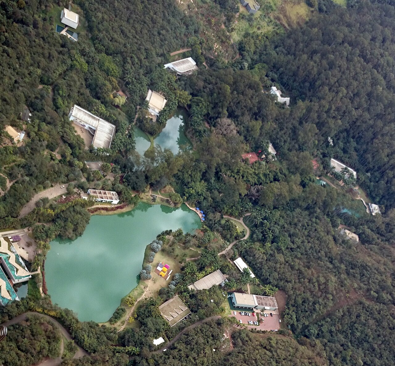 Vista aérea do Instituto Inhotim: galerias brancas, lagos e mata em Brumadinho.